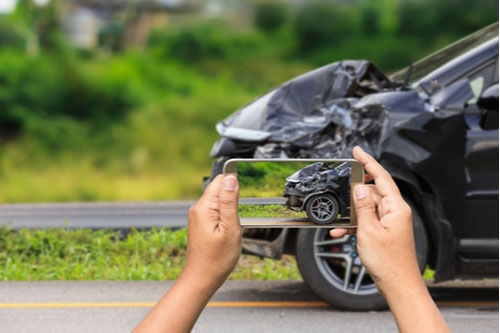 a driver taking cell phone pictures of a crash, Delray Beach car accident lawyer concept