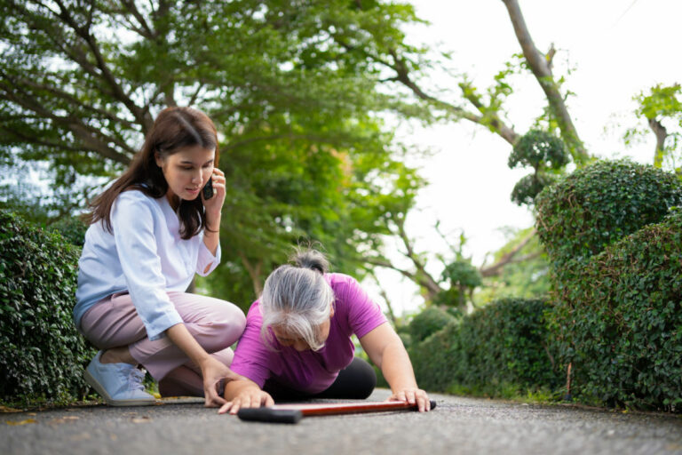 Asian senior woman fell down on lying floor because faint and limb weakness and pain from accident and woman came to help support and call emergency. Concept of old elderly insurance and health care
